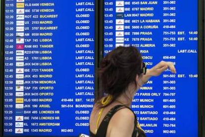 Una viajera consulta el panel de información de vuelos ayer en el aeropuerto del Prat.