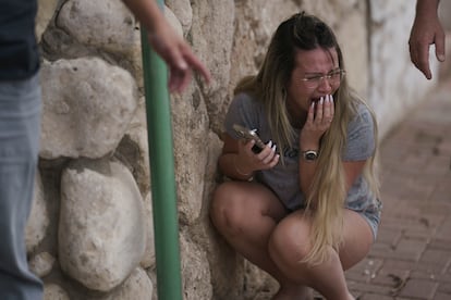 Una mujer israelí se cubre del fuego, a causa de un ataque lanzado desde la Franja de Gaza a Ashkelon, en sur de Israel, este miércoles.