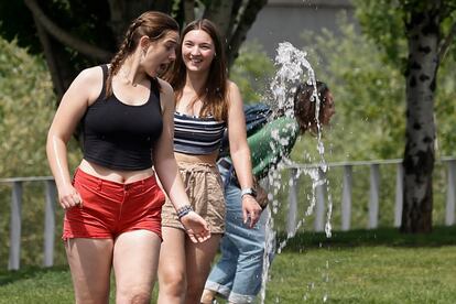 Dos jóvenes se refrescan con una fuente en Madrid.