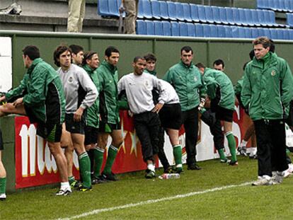 Piterman pasa por delante de algunos jugadores que estiran músculos en una valla, mientras otros le ovbservan.