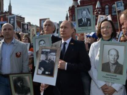 Vladímir Putin, presidente ruso (en el centro), sostiene una foto de su padre, que combatió en la II Guerra Mundial, este sábado en Moscú.