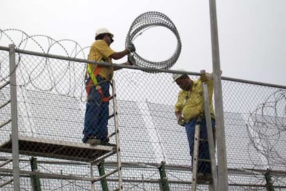 Dos operarios reparan la concertina de la valla que separa España y Marruecos, en Melilla, el pasado 2 de octubre.