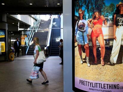 A shopper walks pass advertising billboards for Boohoo and for 'Pretty Little Things', a Boohoo brand, at Canary Wharf DLR station in central London, Britain, September 17, 2018. REUTERS/James Akena