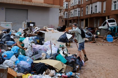 Un hombre deposita una bolsa de basura en una calle de Paiporta.