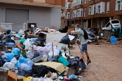 Un hombre deposita una bolsa de basura en una calle de Paiporta (Valencia), este lunes.