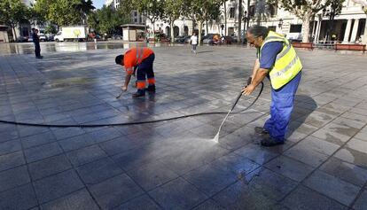 Dos operarios de la contrata de limpieza baldean la plaza del Ayuntamiento de Valencia. 