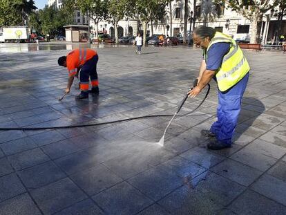 Dos operarios de la contrata de limpieza baldean la plaza del Ayuntamiento de Valencia. 