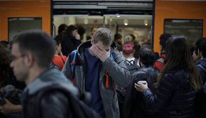 Pasajeros en la estación de Sants, ante un tren de Rodalies.