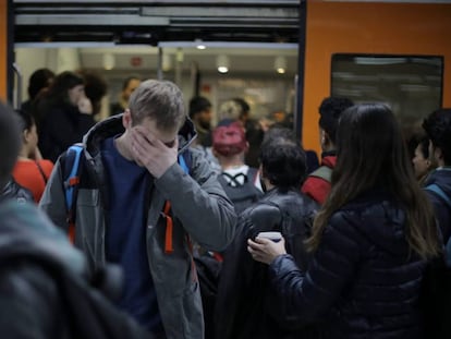 Passatgers a l'estació de Sants, davant un tren de Rodalies.