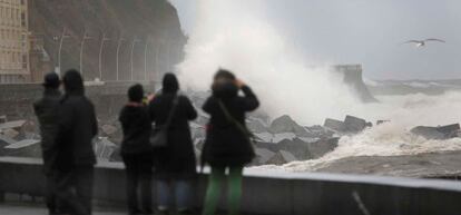 Varias personas fotografían este martes el oleaje en San Sebastián.