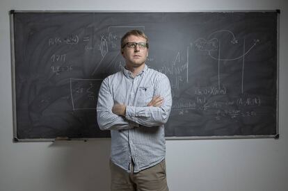 El matemático de Minesota, Jared Aurentz, en una sala del Instituto de Ciencias Matemáticas de Madrid. En la pizarra, partes de las fórmulas que representan la inteligencia artifical que aprende las reglas del dominó.