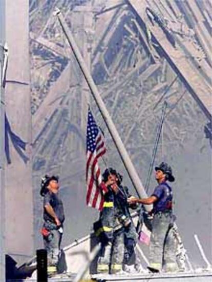 Unos bomberos colocan una bandera de EE UU sobre las ruinas de las Torres Gemelas.