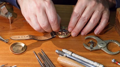 Las manos de una persona reparando un reloj de pulsera.