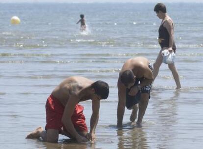 Dos bañistas buscaban coquinas en la playa de Punta Umbría (Huelva) el pasado domingo.