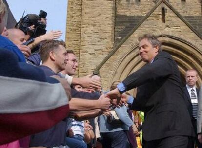 Tony Blair saluda a los vecinos a la puerta de una iglesia.