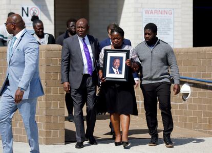 Caroline Ouko, mother of Irvo Otieno, holds a portrait of her son as she walks out of the Dinwiddie Courthouse with attorney Ben Crump, center left, and her older son, Leon Ochieng, in Dinwiddie, Va., on Thursday, March 16, 2023.