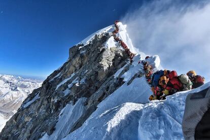 Una gran cola de personas esperan su turno para tocar la cima del Everest en la arista cimera de la montaña más alta del mundo. Muchos equipos tuvieron que hacer fila durante horas para llegar a la cumbre, arriesgándose a las heladas y el mal de altura. Dos personas perecieron en el intento de hollarla.