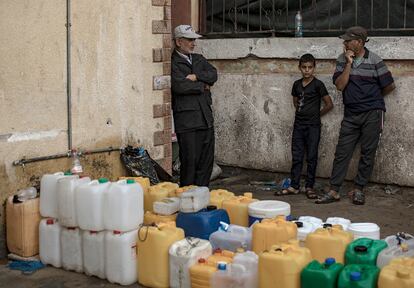 Tres personas esperan para rellenar bidones de agua en el interior del hospital Nasser de Jan Yunis, este martes.  