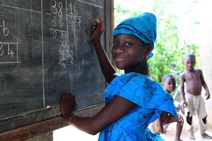 Fatimata Bagayogo (11 años) estudia en casa durante la pandemia, en Odienné, Costa de Marfil. Como las escuelas están cerradas, ella asiste a clases por televisión y practica matemáticas en una pizarra.