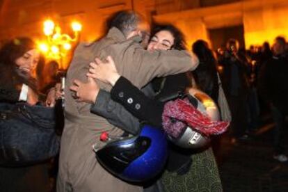 Dos italianos celebran la marcha de Berlusconi a las puertas del palacio presidencial, en Roma.