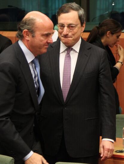 Luis de Guindos ha afirmado antes de la reunión del Eurogrupo que España ha hecho todo lo que estaba en su mano para salir de la crisis y ahora hace falta cooperación europea. En la imagen, el ministro de Economía español (izquierda) pasa junto a Mario Draghi, presidente del BCE