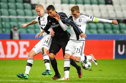 Cristiano Ronaldo (centro) del Real Madrid disputa el balón con Jakub Rzezniczak (derecha) y Adam Hlousek (izquierda) del Legia de Varsovia.