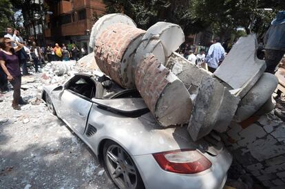 Un cotxe ha quedat totalment destruït després de rebre l'impacte de la runa d'un edifici afectat pel terratrèmol, a Ciutat de Mèxic.