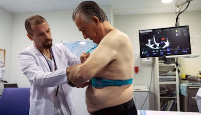El doctor Jorge Pagola, investigador del VHIR, coloca al paciente Meriton Bacuña, un chaleco Holter que registra la actividad del corazón