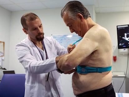 El doctor Jorge Pagola, investigador del VHIR, coloca al paciente Meriton Bacu&ntilde;a, un chaleco Holter que registra la actividad del coraz&oacute;n