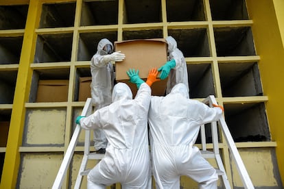 Trabajadores del cementerio Parques de la Paz meten una caja de cartón con un fallecido presuntamente por COVID-19 en una tumba, el 20 de abril de 2020, en Daule, provincia de Guayas (Ecuador).