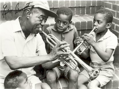 Louis Armstrong, enseñando a tocar la trompeta a dos niños, en una fotografía expuesta en su Casa Museo firmada por él.