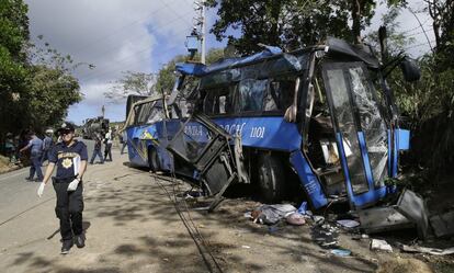 Un policía camina al lado de los restos de un autobús estrellado en una carretera de Rizal, al este de Manila (Filipinas). Más de una docena de estudiantes universitarios han perdido la vida después de que el autobús se accidentara debido a un problema derivado del sistema de frenado.