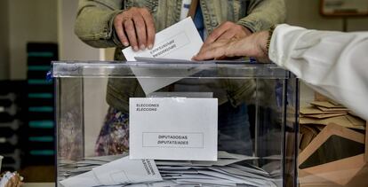Una persona deposita su voto en una urna electoral, en Cataluña.