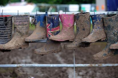 Botas de agua llenas de barro decoran una valla durante el festival celebrado en Pilton (Reino Unido), el 26 de junio de 2016.