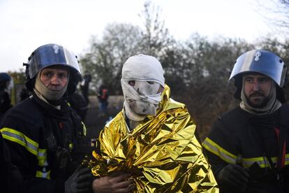 Dos bomberos asisten a un agente antidisturbios de la gendarmería francesa herido tras recibir el impacto de un cocktail molotov durante los enfrentamientos con manifestantes, en Notre Dame des Landres (Francia).