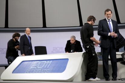 Técnicos de sonido colocan los micrófonos a Rubalcaba y Rajoy poco antes de empezar el debate.