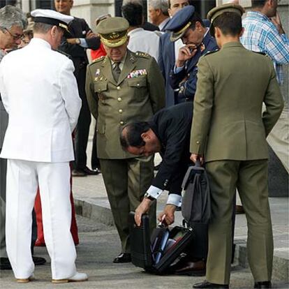 El ministro de Defensa, José Bono, agachado, rodeado de militares en el patio del Congreso.