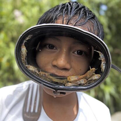 Un niño de una familia de campesinos quechuas guarda en las gafas
los peces que acaba de sacar del río.