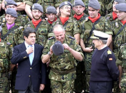 El Rey, acompañado de Federico Trillo, se pone una gorra para posar con las tropas españolas en Istok.