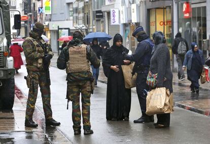 Soldats i policies revisen la documentació d'una dona en un carrer comercial de Brussel·les.