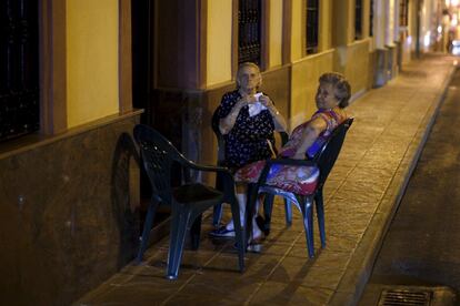 Dos mujeres han sacado sillas a la puerta de su casa en Ronda para aprovechar el fresco de la noche.