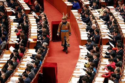 Un delegado con traje tradicional camina entre otros asistentes durante la sesión de apertura de la Asamblea Popular Nacional (APN) en el Gran Palacio del Pueblo, el 5 de marzo.