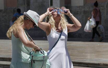 Dos turistas que visitan Valencia alivian el calor con agua. 