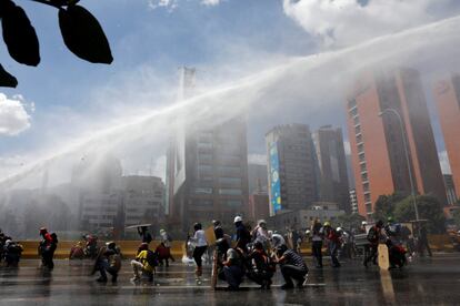 Policía antidisturbios lanzan un chorro de agua contra los manifestantes, durante la manifestación en Caracas.