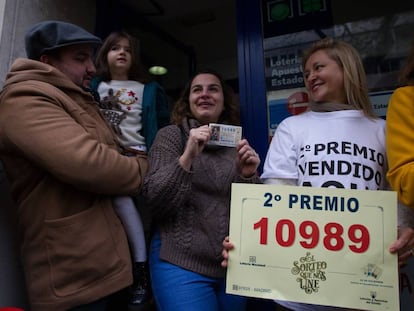 Sandra, junto a su Óscar y su hija Sofía, muestra el décimo premiado ante la mirada de la lotera Carmen Hinojosa Navas.