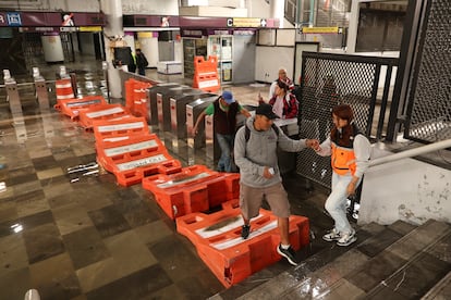 Personas caminan sobre señalizaciones ante la inundación de la estación del metro Pantitlán.