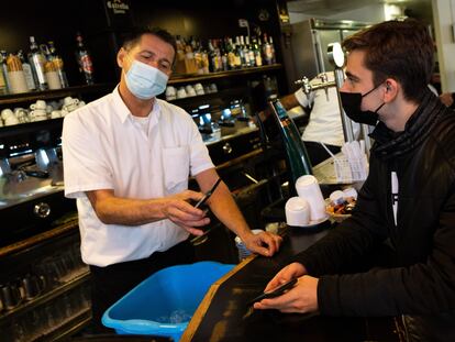 Un camarero escanea el código QR del certificado de vacunación de un cliente en el bar Zurich de Barcelona.