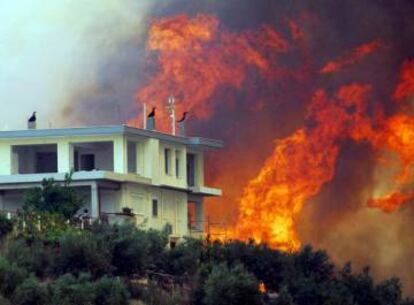 Las llamas arden cerca de una vivienda durante los incendios que afectaron a Grecia en 2007.