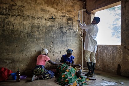 Emmanuel Chipokodzi, asistente médico del centro de salud de Mtosi, Malawi, revisa la medicación de una paciente de cólera mientras los familares de esta la apoyan.