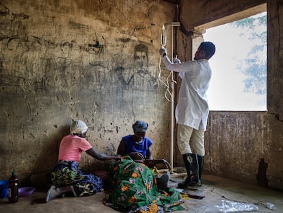 Emmanuel Chipokodzi, asistente médico del centro de salud de Mtosi, Malawi, revisa la medicación de una paciente de cólera mientras los familares de esta la apoyan.